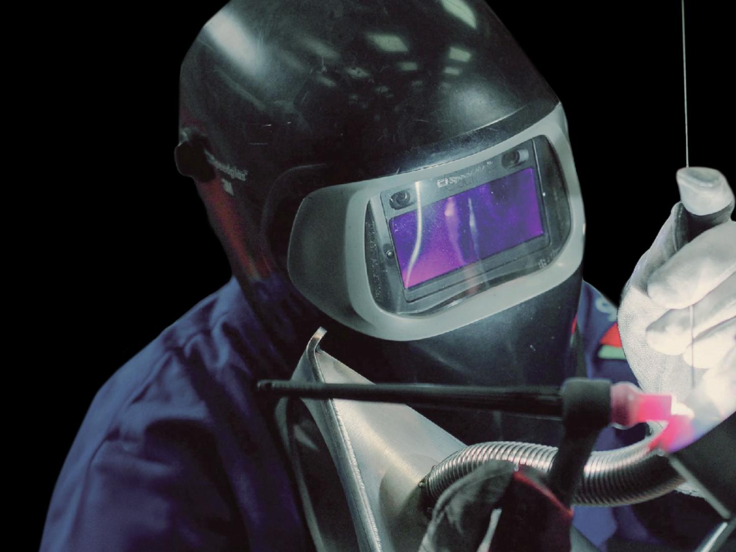 A person welds wearing full body protection