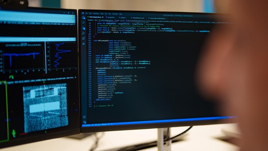 Two screens, on the left there is a scan and some graphs, on the screen on the right is programming code.