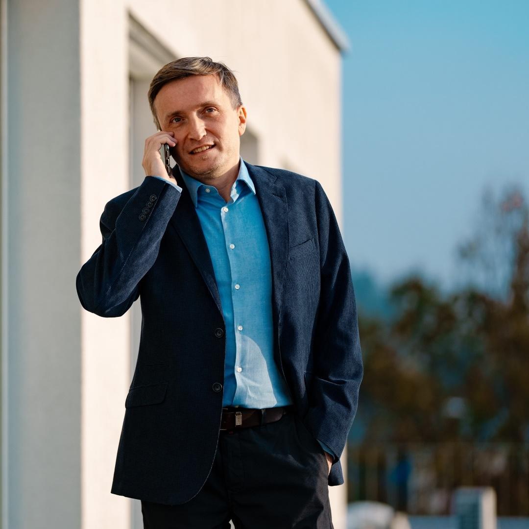 Adam Strzelecki is standing on the rooftop terrace and talking on his phone.