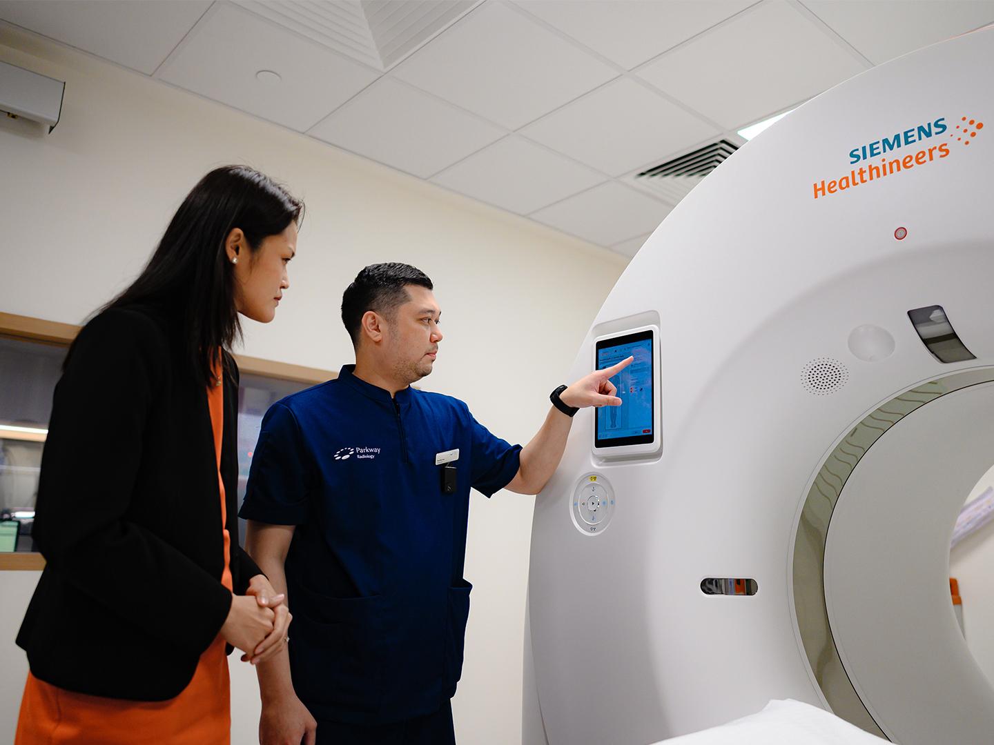 Technologist and Tan Yujuan in front of a CT Scanner