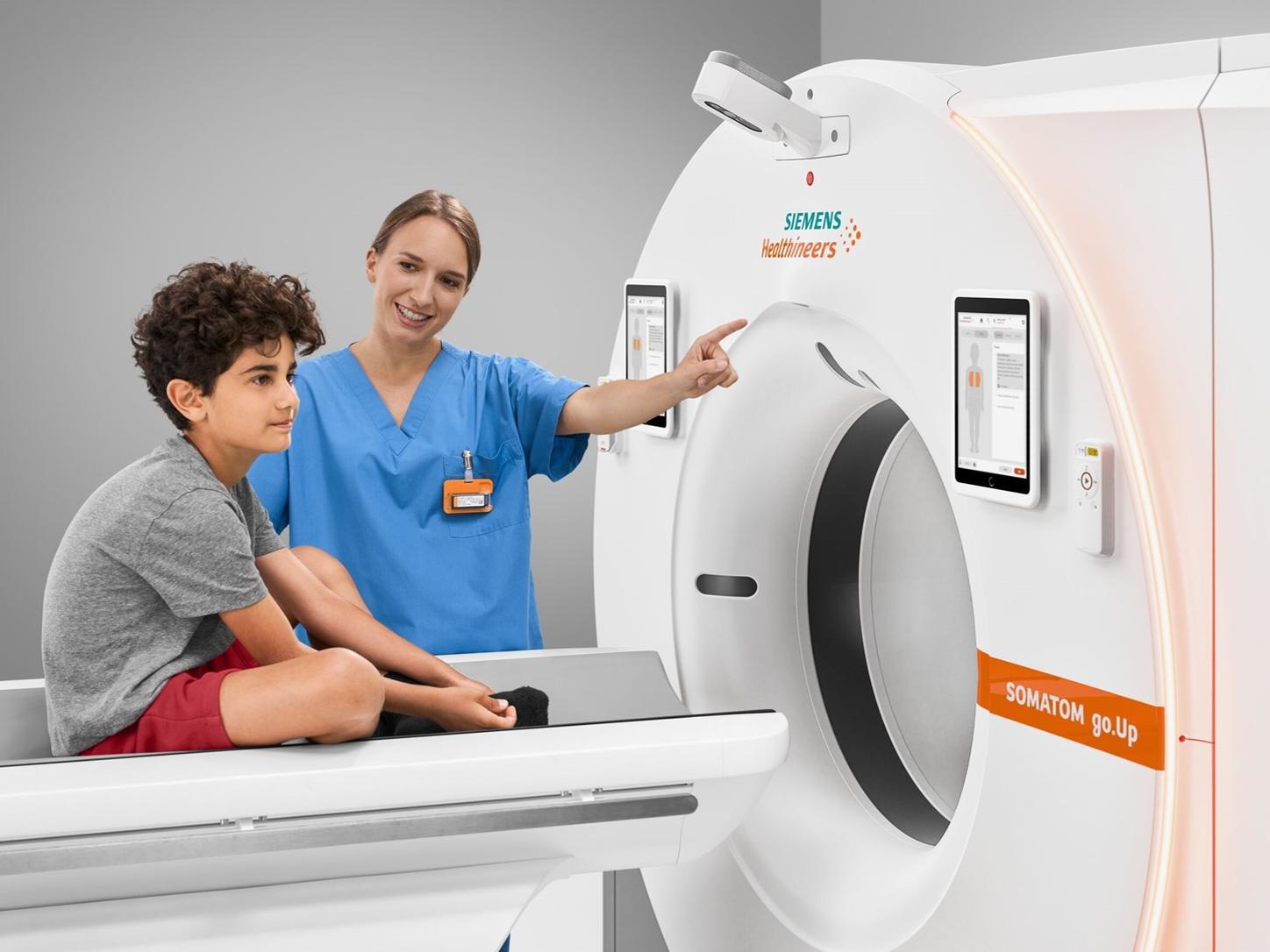 Woman showing boy CT scanner