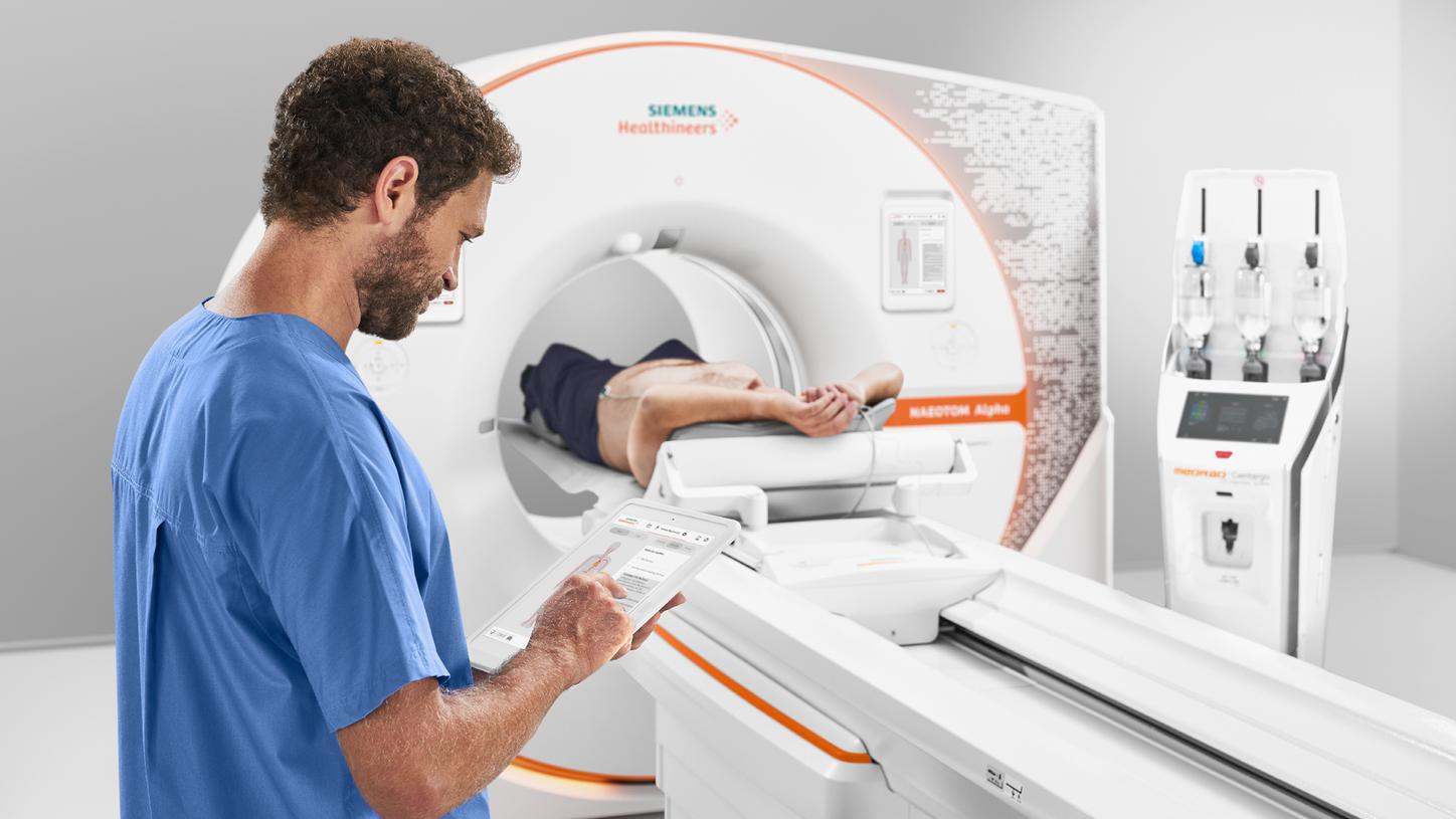 A technician controls a CT scan using a tablet and GO technologies.