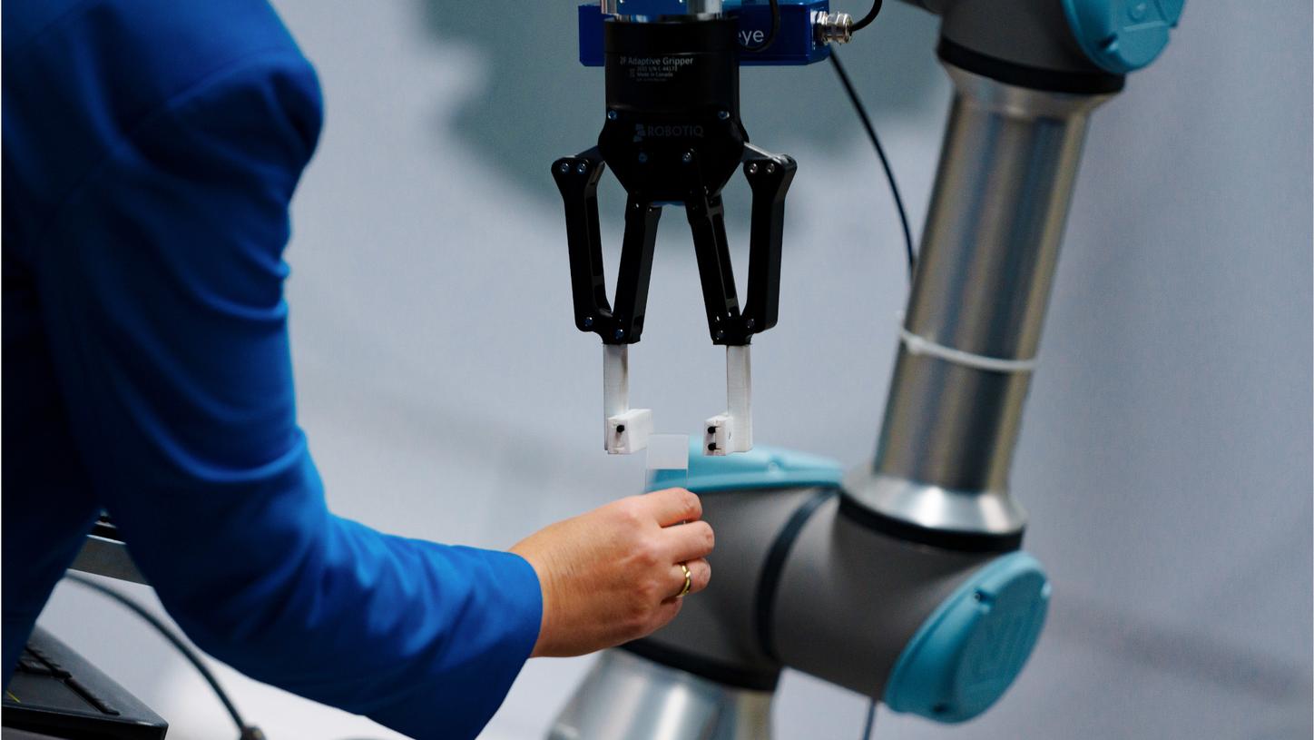 Photo from the innovation lab. In a close-up, we see the hand of Chiheb Dahmani's colleague Claudia Igney handing a glass slide to the gripper of the Vanessa assistant robot prototype.